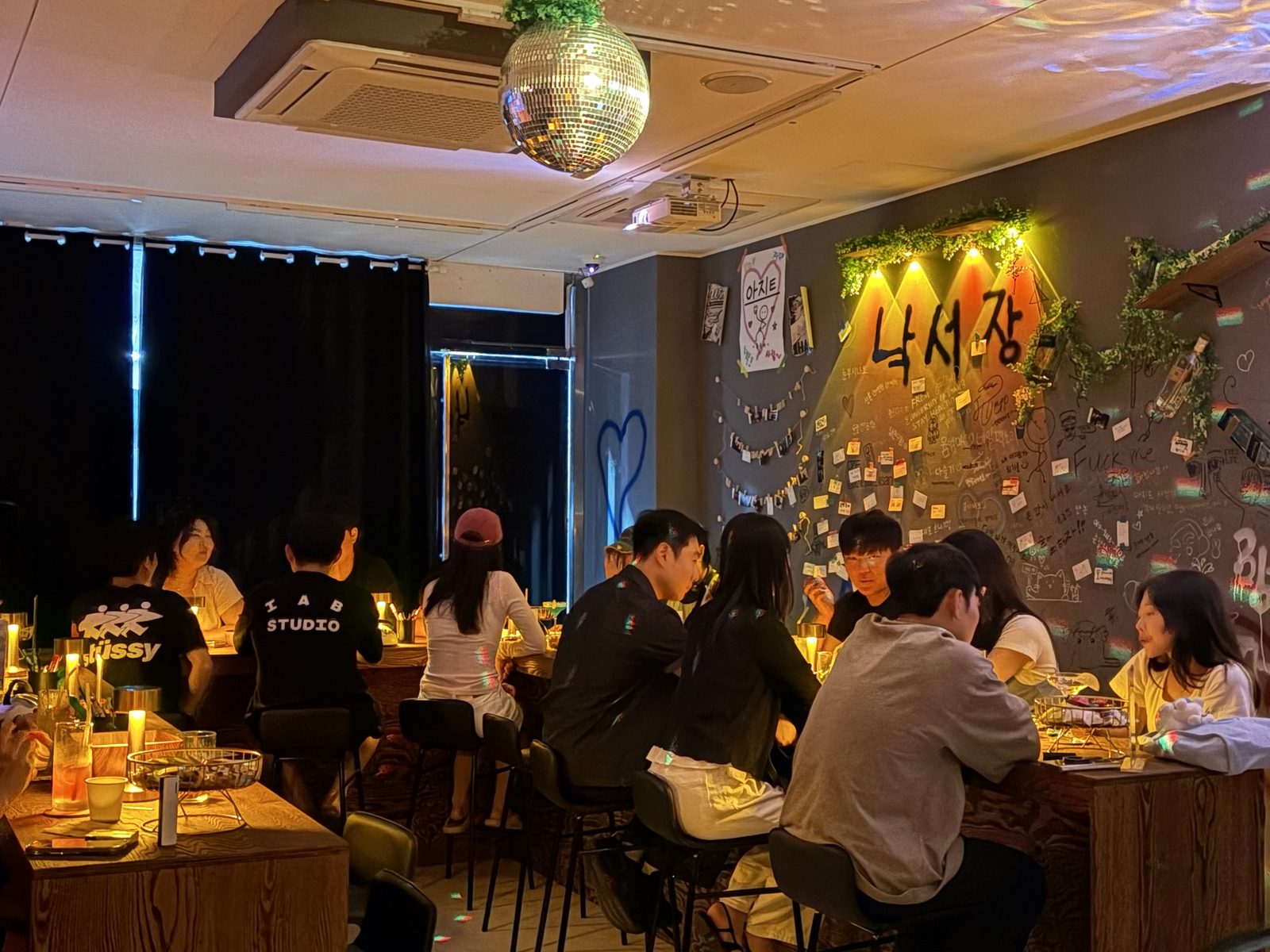 손님들로 가득 찬 아지트 혼술바 — 미러볼과 낙서장 벽